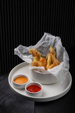 Menü için beyaz bir tabakta soslu tempura içinde karidesler.