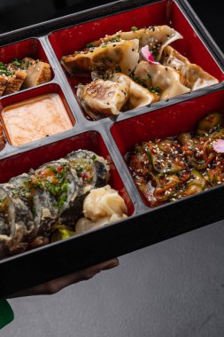 Gyoza, sushi, somon ve tempura içeren Bento kutusu menü için izole edilmiş.