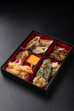 Gyoza, sushi, somon ve tempura içeren Bento kutusu menü için izole edilmiş.