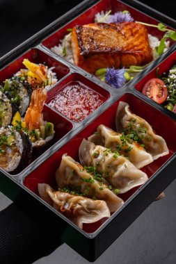 Gyoza, sushi, somon ve tempura içeren Bento kutusu menü için izole edilmiş.