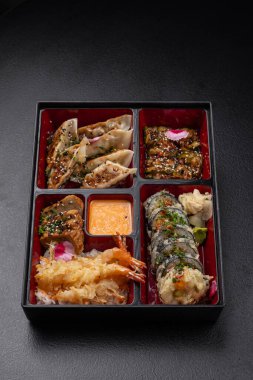 Gyoza, sushi, somon ve tempura içeren Bento kutusu menü için izole edilmiş.