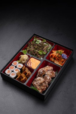 Suşi, kimchi, tofu, tempura ve soslu Japon usulü bento kutusu.