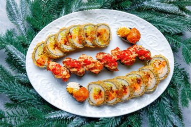 Suşi, Noel ağacı arka planında beyaz bir tabakta, yeni yıl temalı.