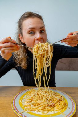 Kafede makarna yiyen karizmatik bir kız. Yüzünde sanatsal bir ifade var..