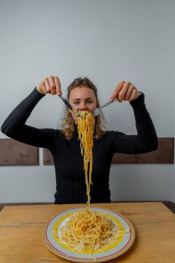 Kafede makarna yiyen karizmatik bir kız. Yüzünde sanatsal bir ifade var..