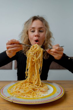 Kafede makarna yiyen karizmatik bir kız. Yüzünde sanatsal bir ifade var..