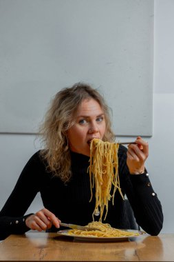 Kafede makarna yiyen karizmatik bir kız. Yüzünde sanatsal bir ifade var..