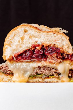 Kesikte sulu burger. Pirzola, peynir, karamelli kiraz ve sos. Metin için boşluk ile izole edilmiş