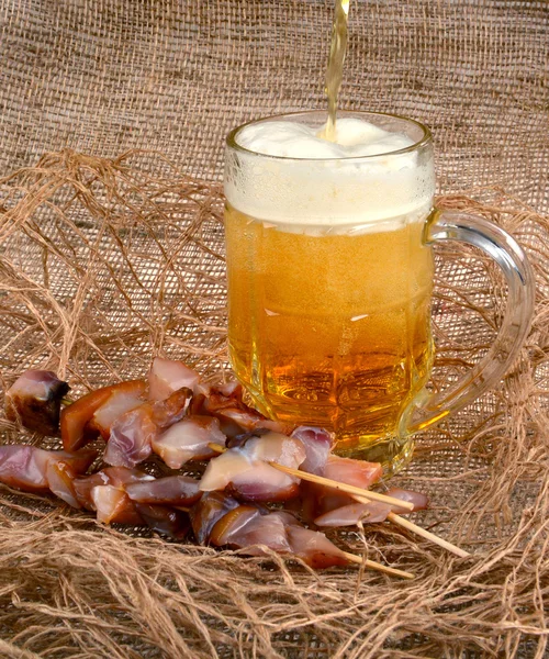 Copo de cerveja e espetos de peixe-gato em um fundo marrom — Fotografia de Stock