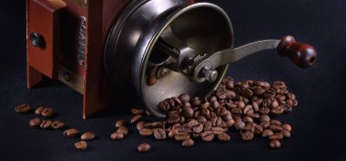 Kahve öğütücü ile siyah bir zemin üzerine kahve çekirdekleri