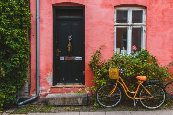 Copenhagen, Denmark - September, 24th, 2015. Street, door, window, red wall and orange hipster bike with basket in Copenhagen Old Town.