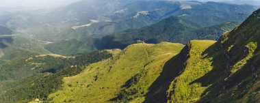 Stara Planina Ulusal Parkı 'ndaki Kopren Dağı zirvesinden yaz manzarası. Balkan Dağları 'nın vahşi doğası boyunca uzanan dağ yamaçları ve dağ vadileri boyunca dramatik gölgelerle dolu Panorama.