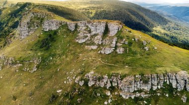 Stara Planina Ulusal Parkı 'ndaki Tri Cuke zirvesinin insansız hava aracı görüntüsü veya popüler seyahat merkezi Balkan Dağları. Yeşil yamaçların oluşturduğu panoramik yaz manzarası kayalık çıkıntılar arasında dolambaçlı bir yol..