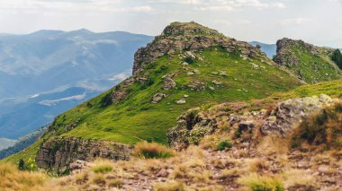 Tri Cuke 'un yaz manzarası kayalık çıkıntılar ve yeşil yamaçlarla zirveye doğru giden dolambaçlı yürüyüş yolu. Balkan Dağları 'nın engebeli doğal güzelliği, Stara Planina Dağları olarak da bilinir..