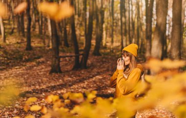Sonbahar ormanında yaprakları dökülen bir kadın. Sarı bere takan, elinde bardak tutan, sıcak içeceklerin tadını çıkaran bir kız. Kadın dinlenme anı, doğada yalnızlık ve dışarıda zaman geçiriyor..