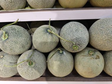 Taze toplanmış karpuzlar karmaşık deri dokusunu sergiliyor bu olgun yeşil meyveler ahşap bir rafta güzelce istiflenmiş.
