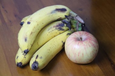 Kahverengi benekli olgun muzlar ve ahşap bir masada sıralanmış taze bir elma hala sağlıklı ve doğal meyvelerle dolu bir hayat.