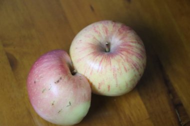 Doğal ahşap bir arka planda duran iki taze elmanın yakın görüntüsü.