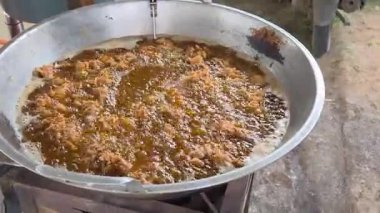 Sıcak yağ güçlü bir şekilde köpürürken, ezilmiş tavuk sokak yemeklerinde geleneksel bir tavada çıtır çıtır altın bir dokuya pişiriyor.