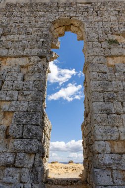 Landscape shot in the Andalusian summer. Barren landscape with blue sky next to Roman ruins. An old, dilapidated historical theater at the ruins of Acinipo, Andalusia, Spain