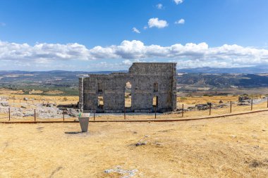 Landscape shot in the Andalusian summer. Barren landscape with blue sky next to Roman ruins. An old, dilapidated historical theater at the ruins of Acinipo, Andalusia, Spain