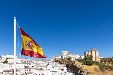 Beyaz köylerin yolu üzerinde. Dağın içinde ve içinde bir sürü beyaz ev bulunan tarihi bir kasabanın manzarası ya da silüeti. İspanyol bayrağı ve Setenil de las Bodegas, Cadiz, Endülüs, İspanya