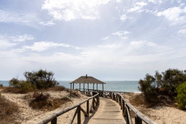 Tahta bir yürüyüş yolu deniz kenarındaki bir kulübeye gider. Atlantik Okyanusu manzarası Pinar De La Almedraba doğa rezervi, Pinares De Rota, Rota, Cdiz, Endülüs, İspanya.