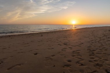 Sahilde nefes kesici bir gün batımı. Ufuktaki denizin üzerinde batan güneşin kumsalını seyret. Atlantik kıyısında Rota, Costa de la Lutz, Cdiz, Endülüs, İspanya yakınlarındaki manzara görüntüleri.