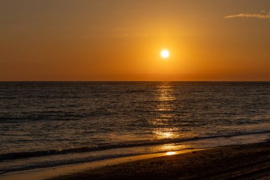 Sahilde nefes kesici bir gün batımı. Ufuktaki denizin üzerinde batan güneşin kumsalını seyret. Atlantik kıyısında Rota, Costa de la Lutz, Cdiz, Endülüs, İspanya yakınlarındaki manzara görüntüleri.