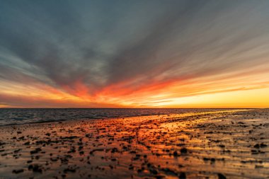 Sahilde nefes kesici bir gün batımı. Gökyüzü en güzel renklerle parıldıyor. Sahilden denize ve ufuk çizgisine bakın Rota, Costa de la Lutz, Cdiz, Endülüs, İspanya.