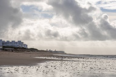Güzel, güzel, geniş kumlu bir sahil, Atlantik kıyısında ıssız. Gökyüzü Rota 'ya doğru, bulutlu gökyüzü Playa de la Costilla, Costa de la Luz, Cadiz, Endülüs, İspanya.