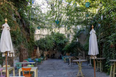 Bir sürü yeşil bitkinin olduğu küçük bir ara sokak. Renkli masalar, sandalyeler ve bir restoranın dekorasyonları. Eski tarihi kasaba, Jerez de la Frontera, Cdiz ili, Endülüs, İspanya.