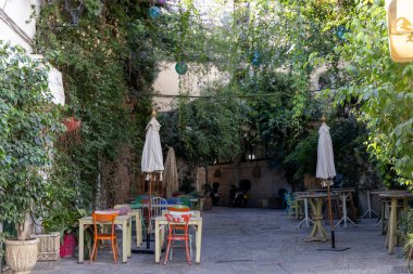Bir sürü yeşil bitkinin olduğu küçük bir ara sokak. Renkli masalar, sandalyeler ve bir restoranın dekorasyonları. Eski tarihi kasaba, Jerez de la Frontera, Cdiz ili, Endülüs, İspanya.