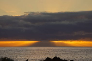 Güneş doğarken eşsiz bir hava durumu fenomeni: Tenerife 'deki Teide volkanının gölgesi, İspanya' nın Kanarya Adaları 'ndaki La Palma adasının lav kıyılarından gözlemlenen denizin üzerinde yoğun bir bulut örtüsüne karşı aşağıdan yansıtılır..
