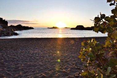 La Palma 'daki Los Cancajos' un kara kumsalında gün doğumu. Volkanik kayaların arkasında güneş patlaması var..