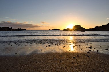 La Palma 'daki Los Cancajos' un kara kumsalında gün doğumu. Volkanik kayaların arkasında güneş patlaması var..