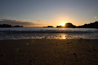 La Palma 'daki Los Cancajos' un kara kumsalında gün doğumu. Volkanik kayaların arkasında güneş patlaması var..