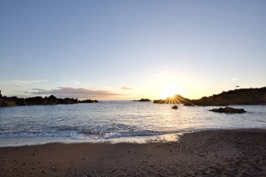 La Palma 'daki Los Cancajos' un kara kumsalında gün doğumu. Volkanik kayaların arkasında güneş patlaması var..