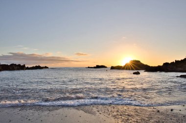 La Palma 'daki Los Cancajos' un kara kumsalında gün doğumu. Volkanik kayaların arkasında güneş patlaması var..