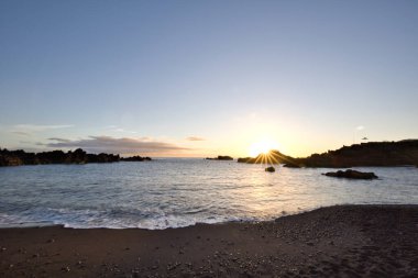 La Palma 'daki Los Cancajos' un kara kumsalında gün doğumu. Volkanik kayaların arkasında güneş patlaması var..
