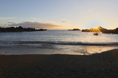 La Palma 'daki Los Cancajos' un kara kumsalında gün doğumu. Volkanik kayaların arkasında güneş patlaması var..