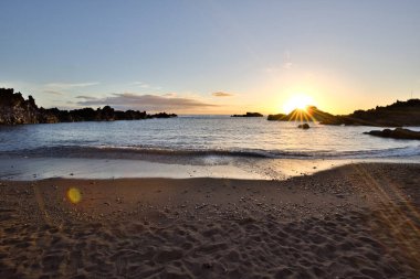 La Palma 'daki Los Cancajos' un kara kumsalında gün doğumu. Volkanik kayaların arkasında güneş patlaması var..