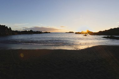 La Palma 'daki Los Cancajos' un kara kumsalında gün doğumu. Volkanik kayaların arkasında güneş patlaması var..