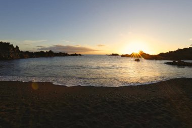 La Palma 'daki Los Cancajos' un kara kumsalında gün doğumu. Volkanik kayaların arkasında güneş patlaması var..