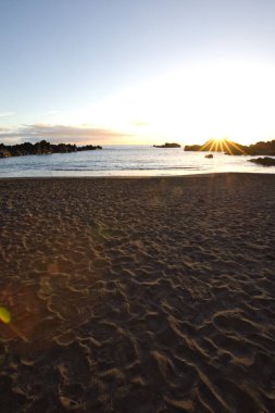 La Palma 'daki Los Cancajos' un kara kumsalında gün doğumu. Volkanik kayaların arkasında güneş patlaması var..