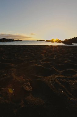 La Palma 'daki Los Cancajos' un kara kumsalında gün doğumu. Volkanik kayaların arkasında güneş patlaması var..