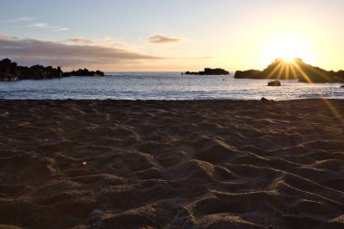 La Palma 'daki Los Cancajos' un kara kumsalında gün doğumu. Volkanik kayaların arkasında güneş patlaması var..