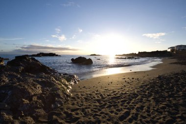 La Palma 'daki Los Cancajos' un kara kumsalında gün doğumu. Volkanik kayaların arkasında güneş patlaması var..