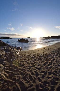 La Palma 'daki Los Cancajos' un kara kumsalında gün doğumu. Volkanik kayaların arkasında güneş patlaması var..