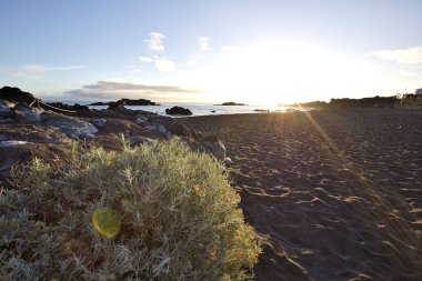 La Palma 'daki Los Cancajos' un kara kumsalında gün doğumu. Volkanik kayaların arkasında güneş patlaması var..